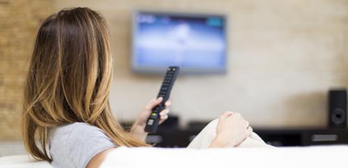Woman with remote watching television.