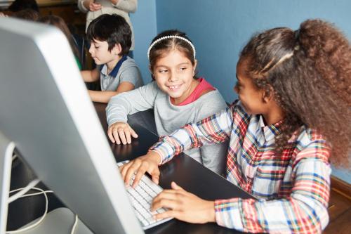 two kids learning together at a computer